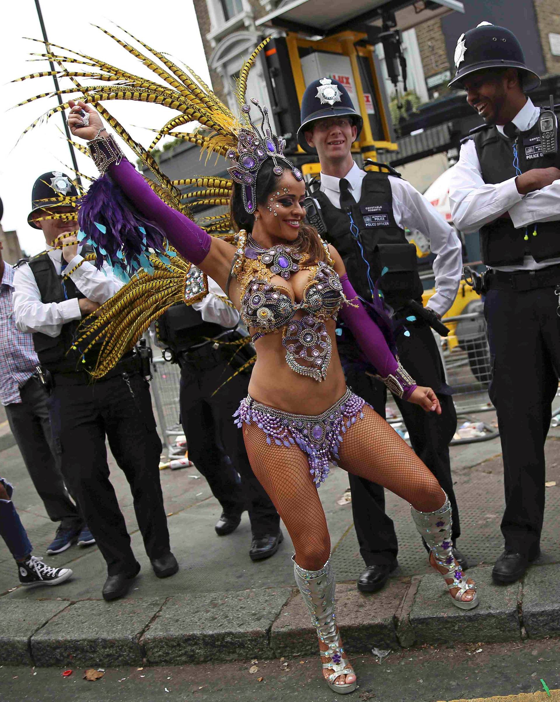 Police look as a performer dances during the Notting Hill Carnival in London