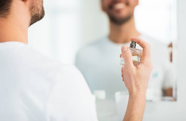 close up of man perfuming with perfume at bathroom