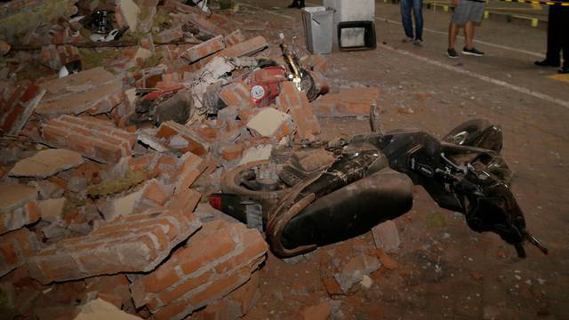 A policeman examines debris that fell and crushed parked motorbikes following a strong earthquake on nearby Lombok island, at a shopping center in Kuta, Bali