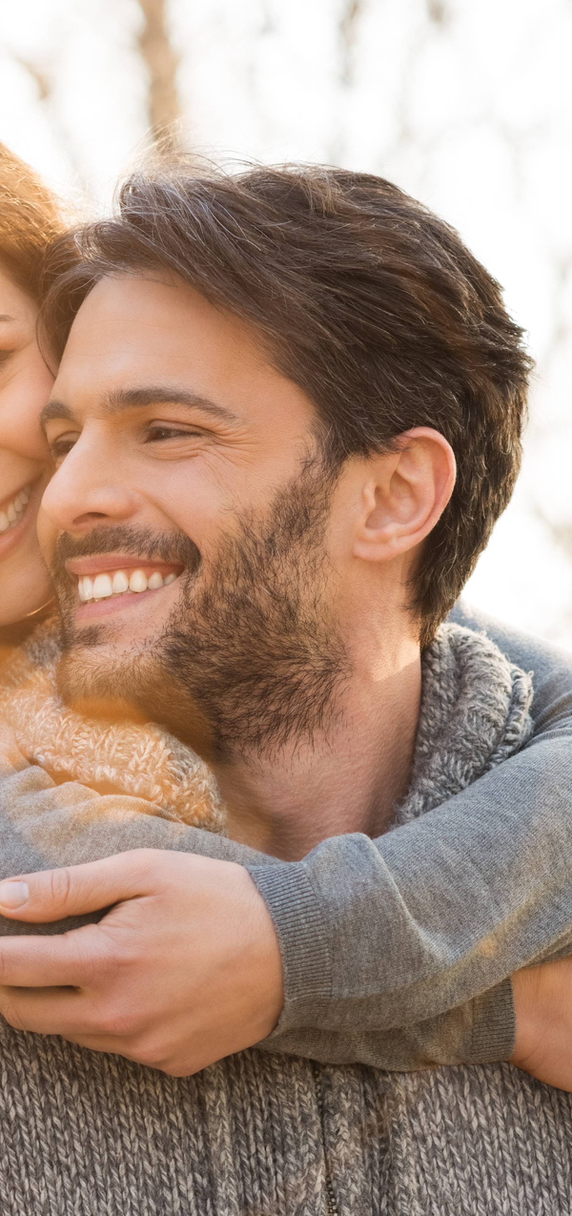 Closeup of smiling man carrying woman piggyback outdoor