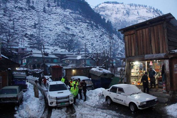 Rescue workers walk the snow-covered road to reach the areas affected by heavy snowfall and avalanches, in Neelum Valley