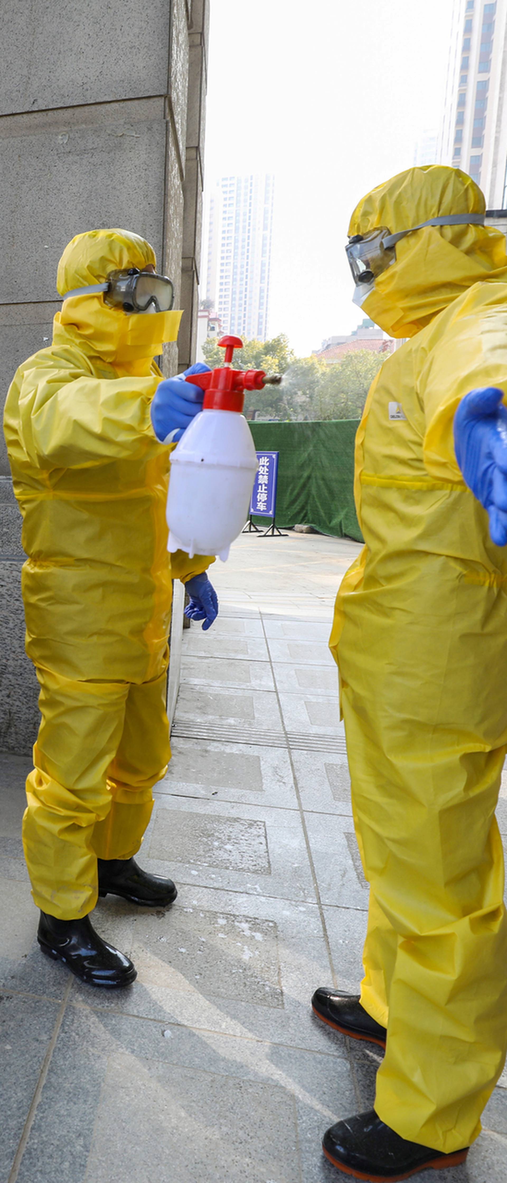 FILE PHOTO: Funeral parlour staff members in protective suits help a colleague with disinfection after they transferred a body at a hospital, following the outbreak of a new coronavirus in Wuhan