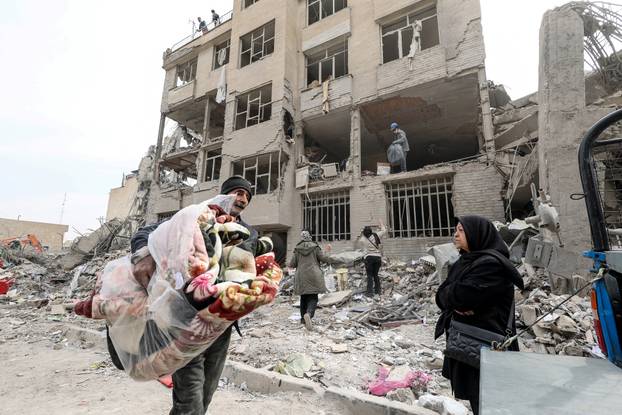 A family gathers the remaining furniture from an apartment damaged by an airstrike, in Tehran
