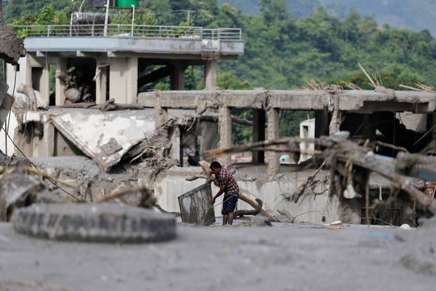 A man salvages his belongings from mud following devastating floods, in Trishuli