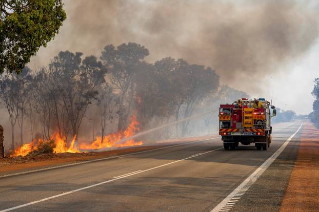 A fire truck puts out bushfire flames in Red Gully, Western Australia