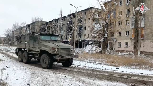 A military vehicle drives past damaged residential buildings in Avdiivka