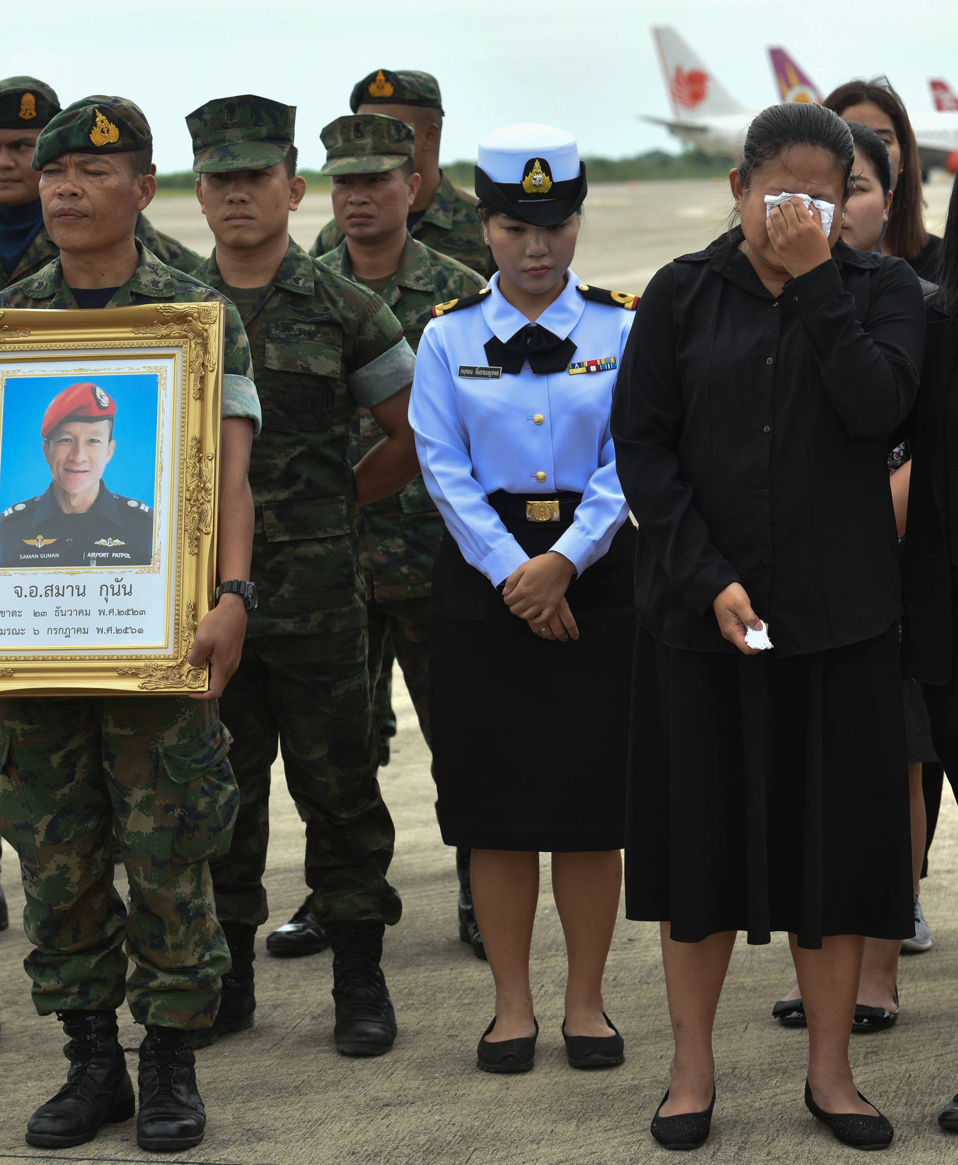 An honour guard hold up a picture of Samarn Kunan as family members weep at an airport in Rayong province