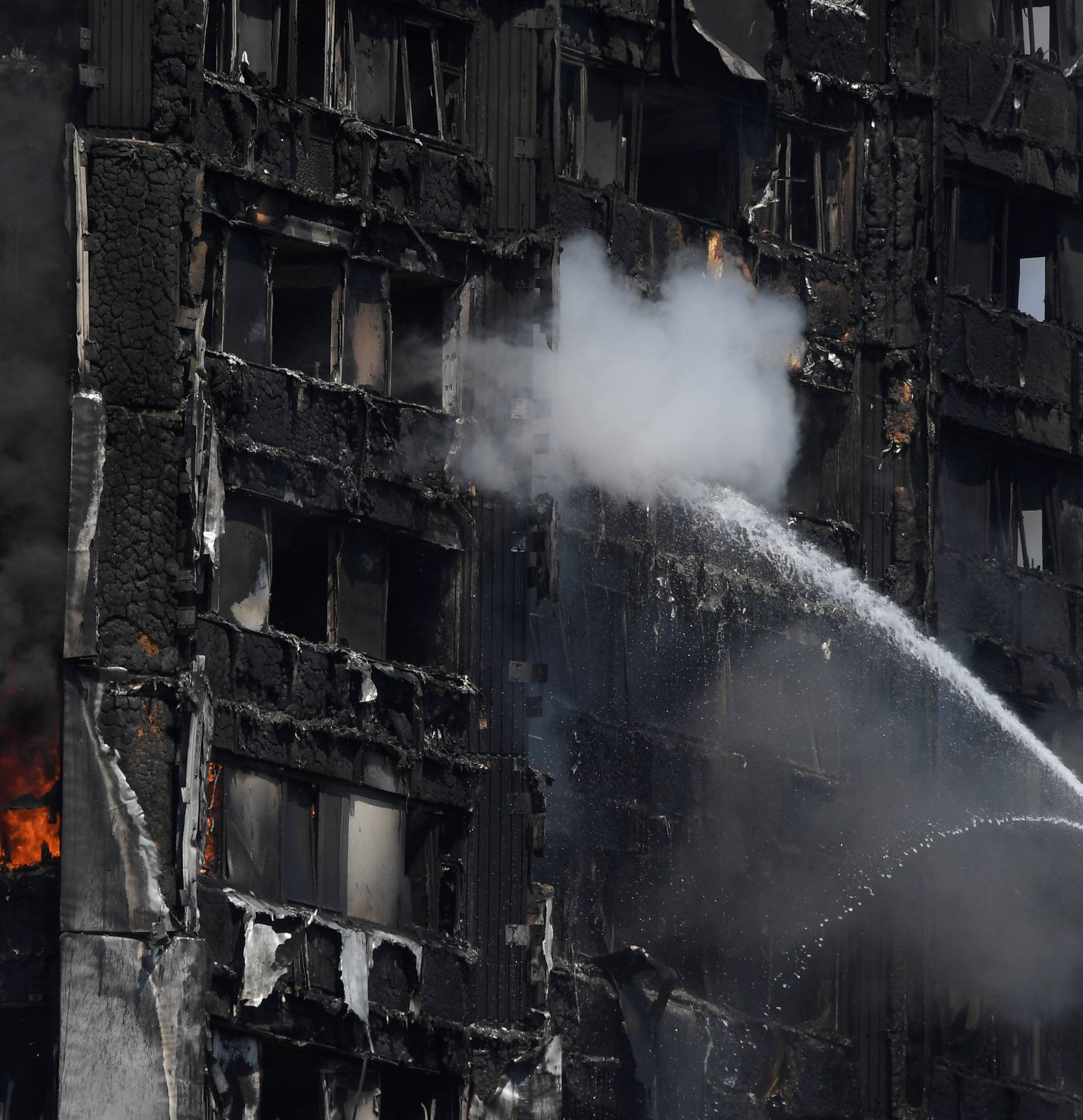 Firefighters direct jets of water onto a tower block severely damaged by a serious fire, in north Kensington, West London