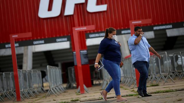 A woman wears a protective face mask in front of the Nilson Nelson Gymnasium as the next UFC Fight Night will be held without fans during the fights, after reports of the coronavirus in Brasilia