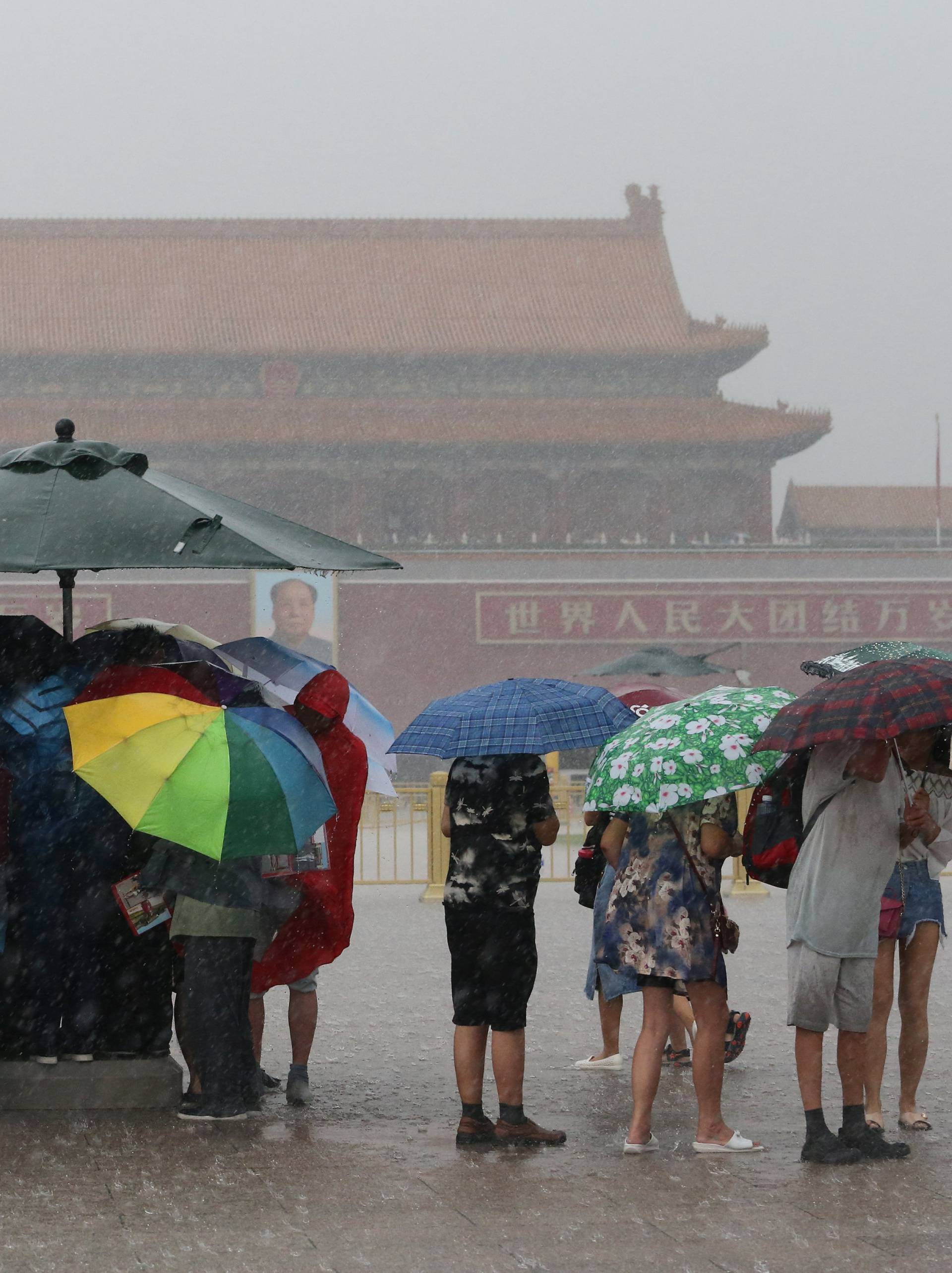 Tourists hold umbrellas as they visit Tiananmen Square during a rainstorm in Beijing