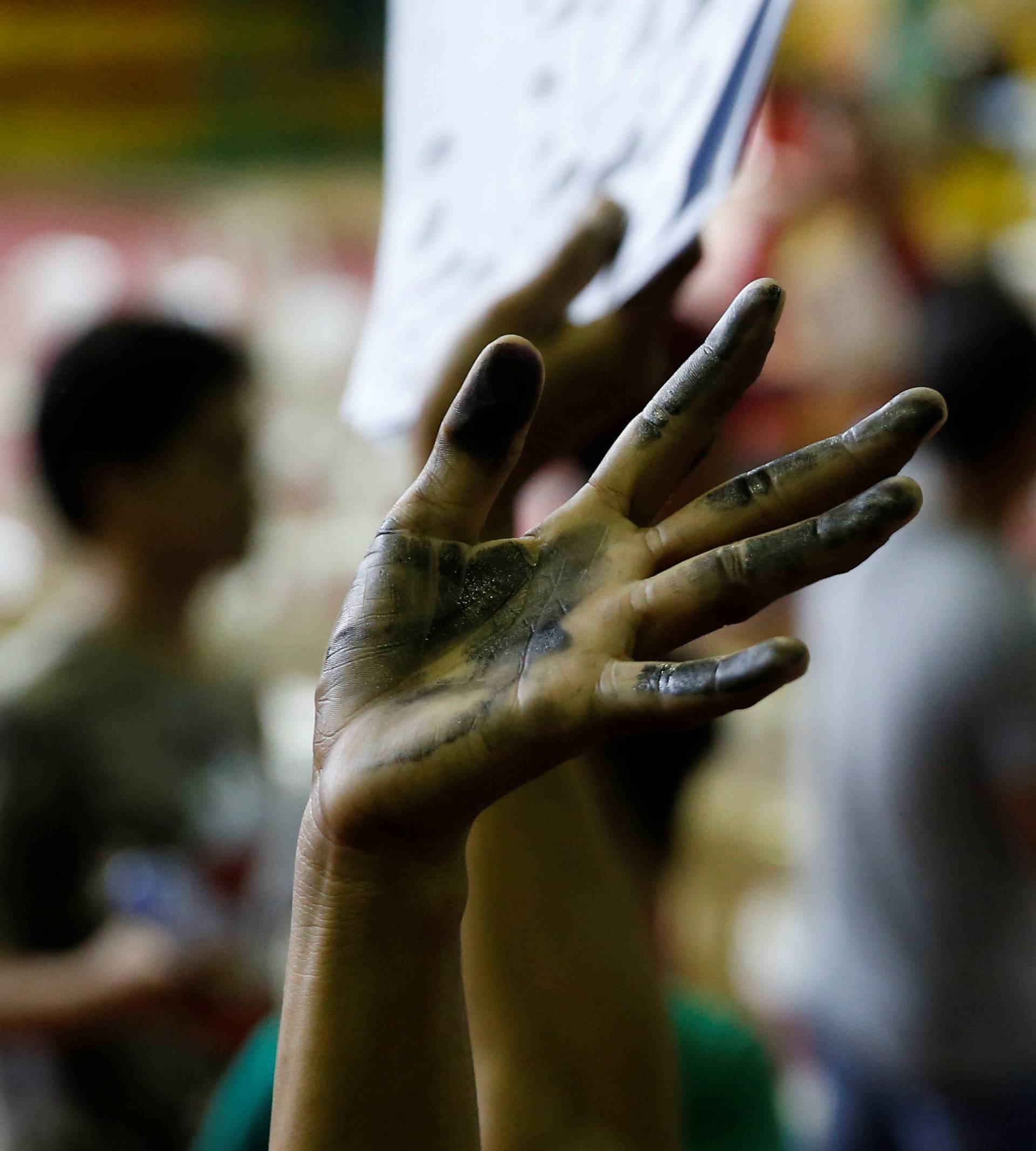 A drug user raises his ink smeared hand after he surrendered to local government officials to take part in a government campaign against drug in Tanauan Batangas, south of Manila