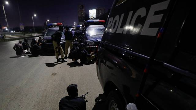 Police officers take position after an attack on a police station in Karachi