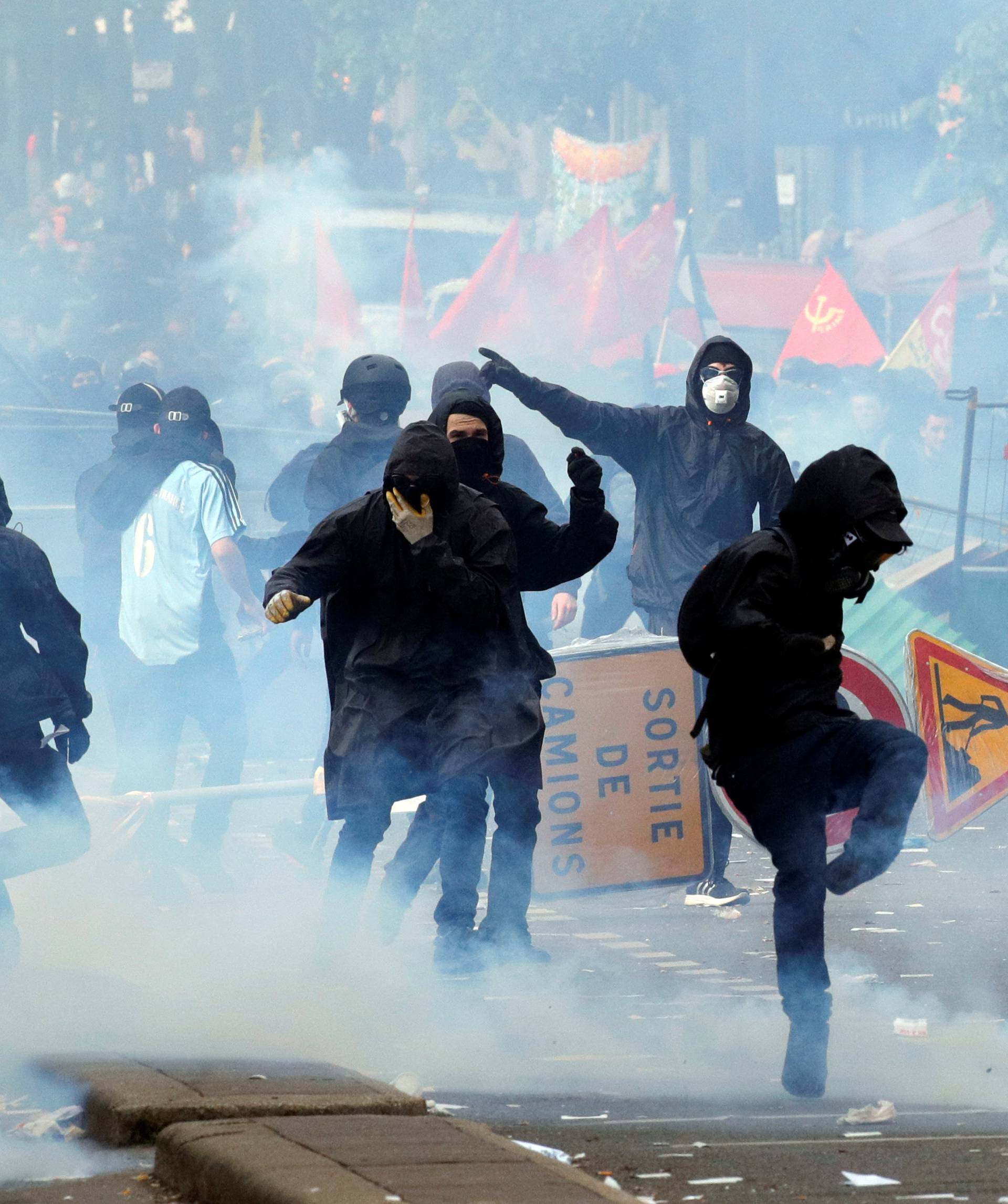 Tear gas floats around masked protesters during clashes with French CRS riot police at the May Day labour union rally in Paris