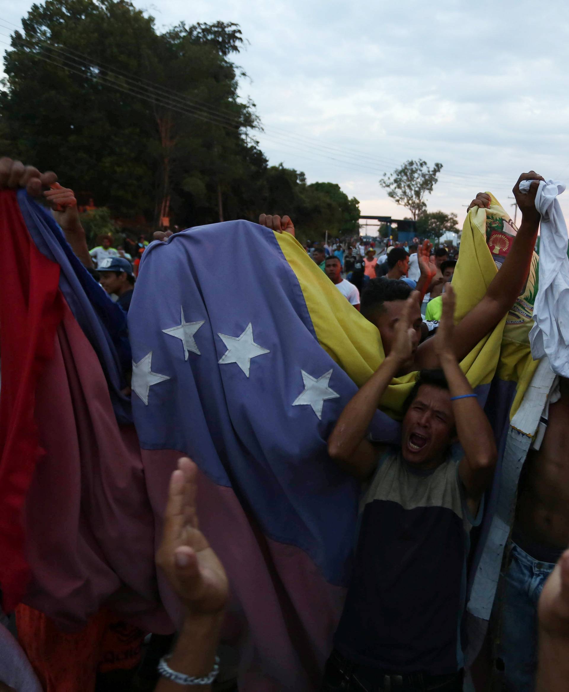 People hold Venezuela's national flag at the border between Venezuela and Brazil in Pacaraima