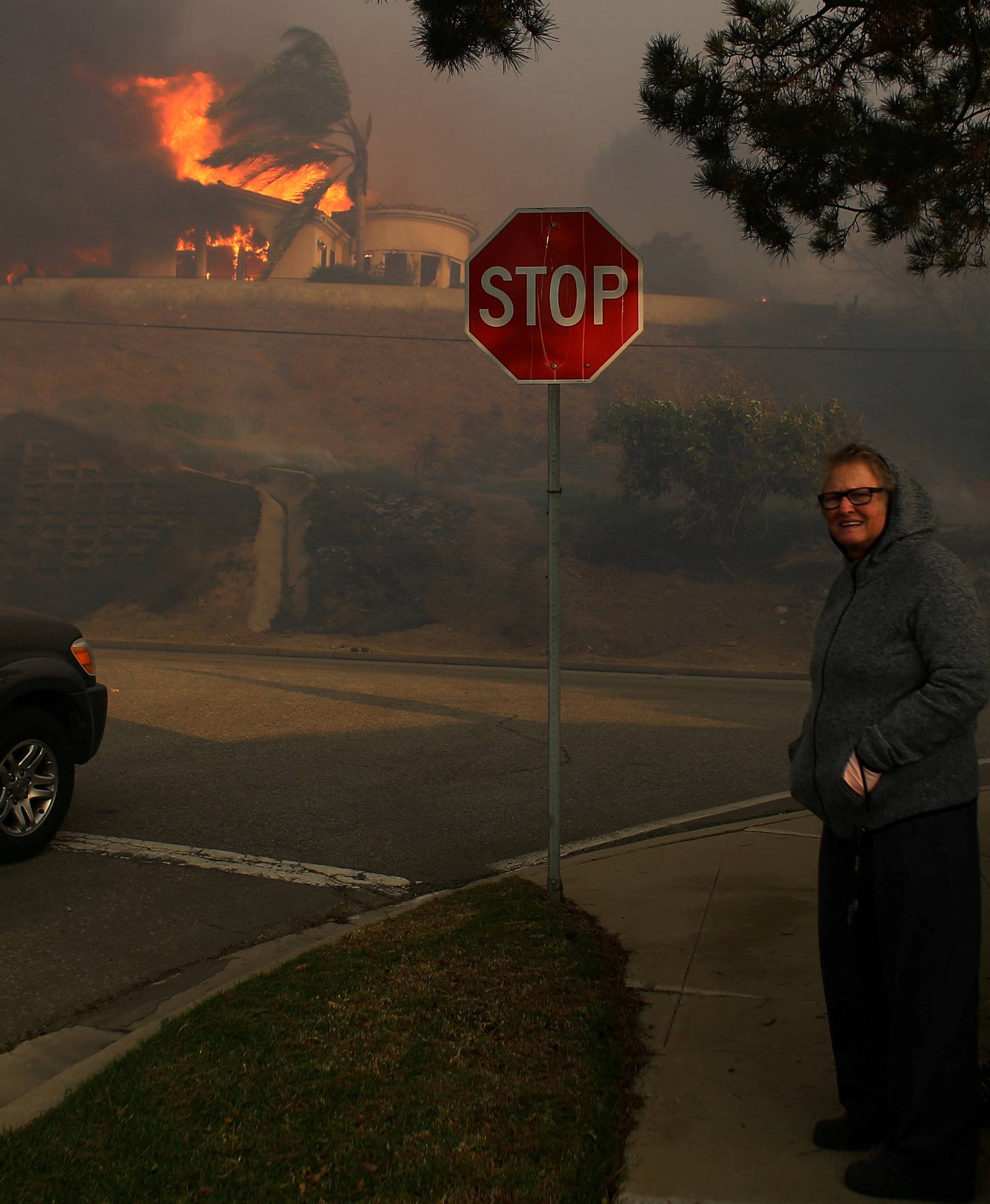 FILE PHOTO: Neighbors watch as a house burns during a wind driven wildfire in Ventura California