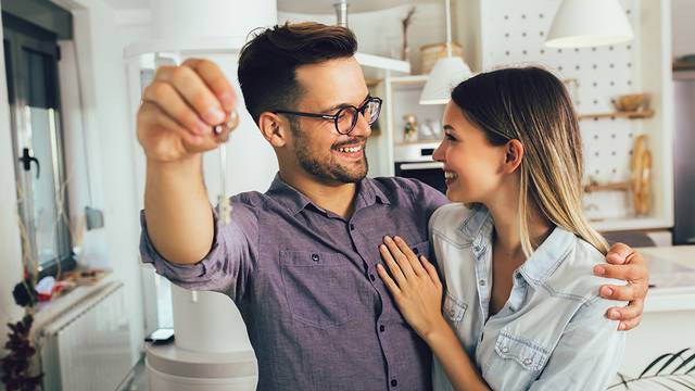 Happy smiling young couple showing a keys of their new house