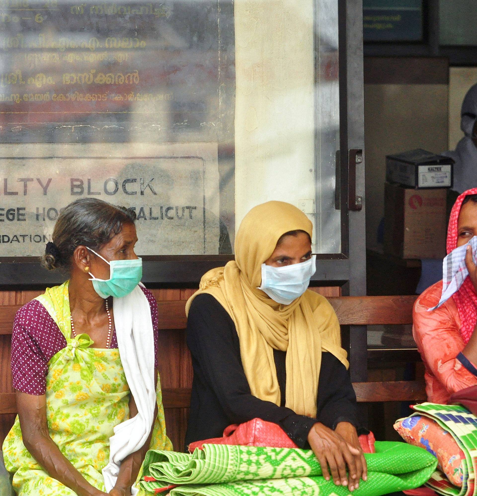People wear masks as they wait outside a casualty ward at a hospital in Kozhikode