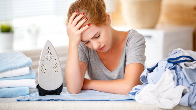 tired woman housewife ironing clothes iron in laundry