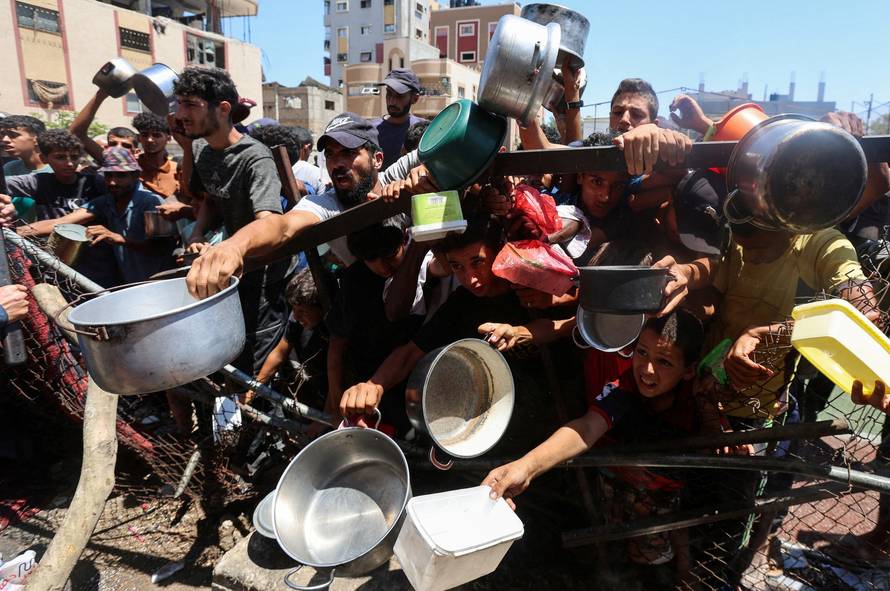 Palestinians gather to receive food from a charity kitchen, amid a hunger crisis, in Nuseirat