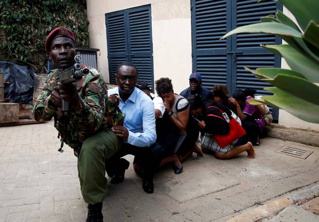 People are evacuated by a member of security forces at the scene where explosions and gunshots were heard at the Dusit hotel compound, in Nairobi