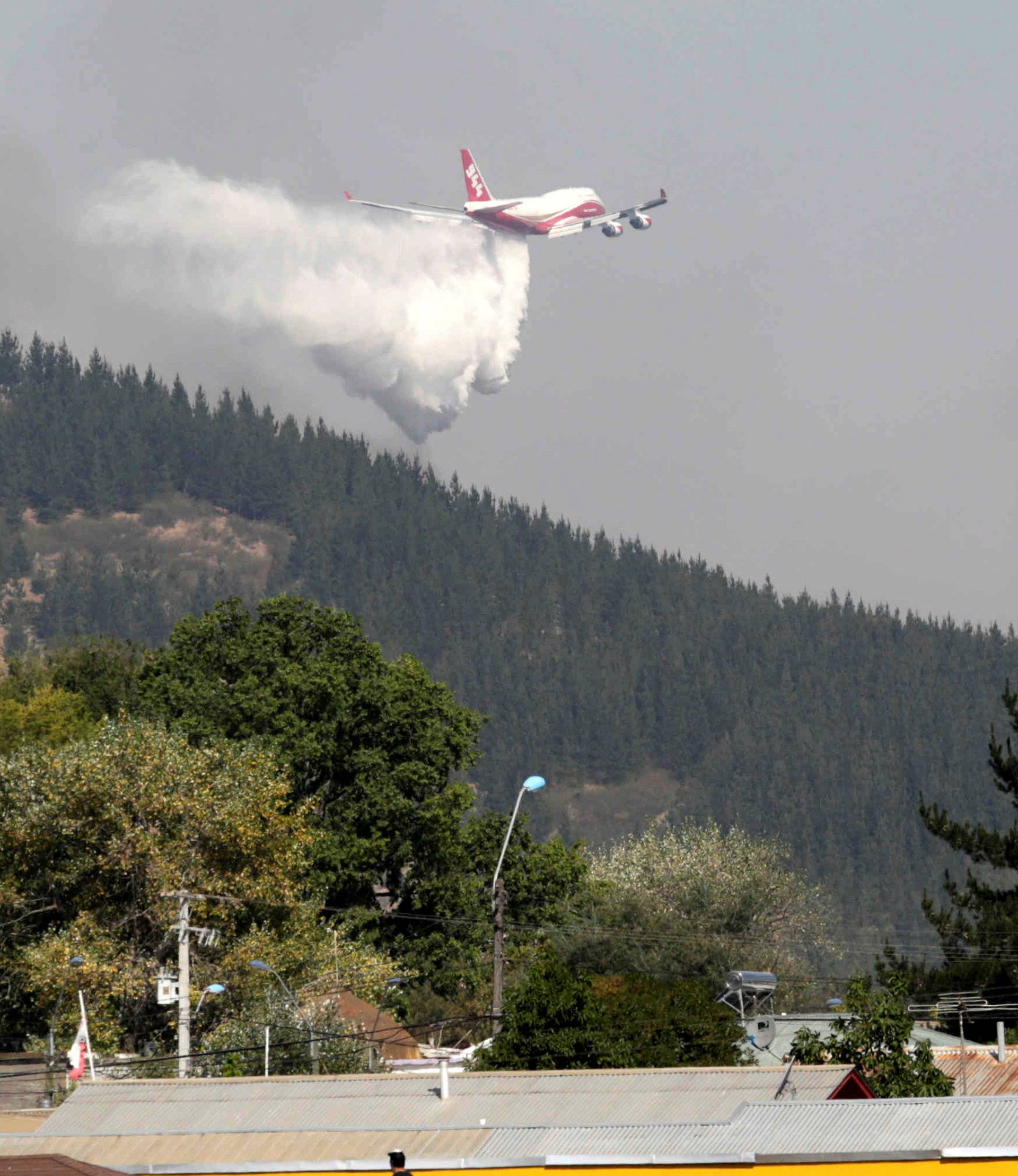 A Boeing 747-400 Super Tanker from the U.S. drops water to extinguish a forest fire in the town of Hualane in the Maule region