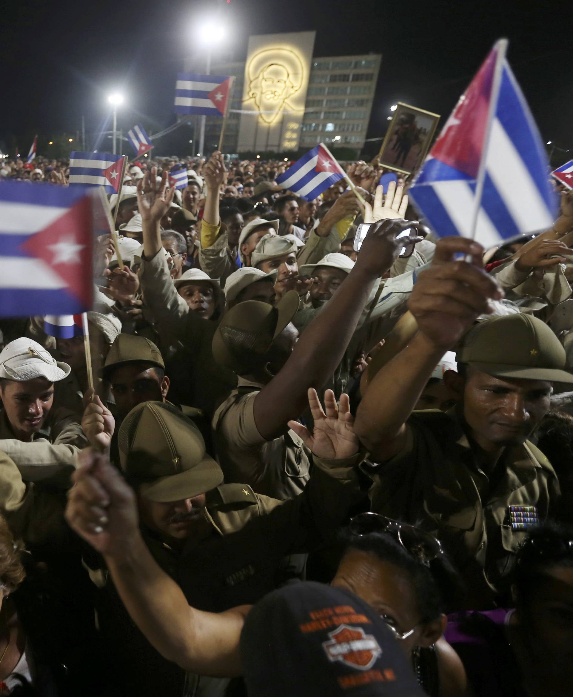 People wave Cuban flags as they attend a massive tribute to Cuba's late President Fidel Castro in Revolution Square in Havana