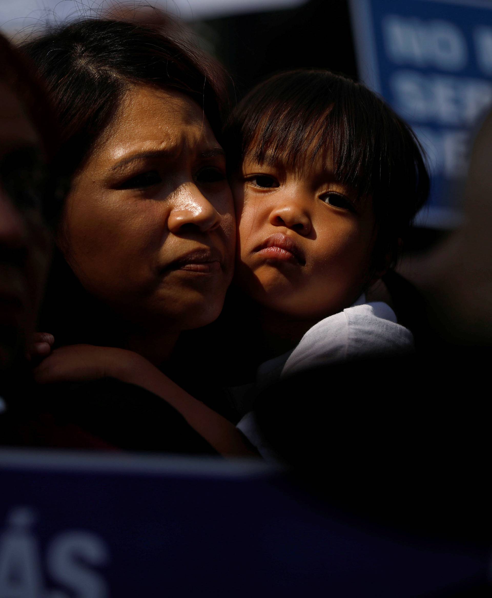 A child embraces a woman as demonstrators hold signs against the Trump administration policy of separating migrant children from their parents at the border during a demonstration outside of City Hall in Los Angeles