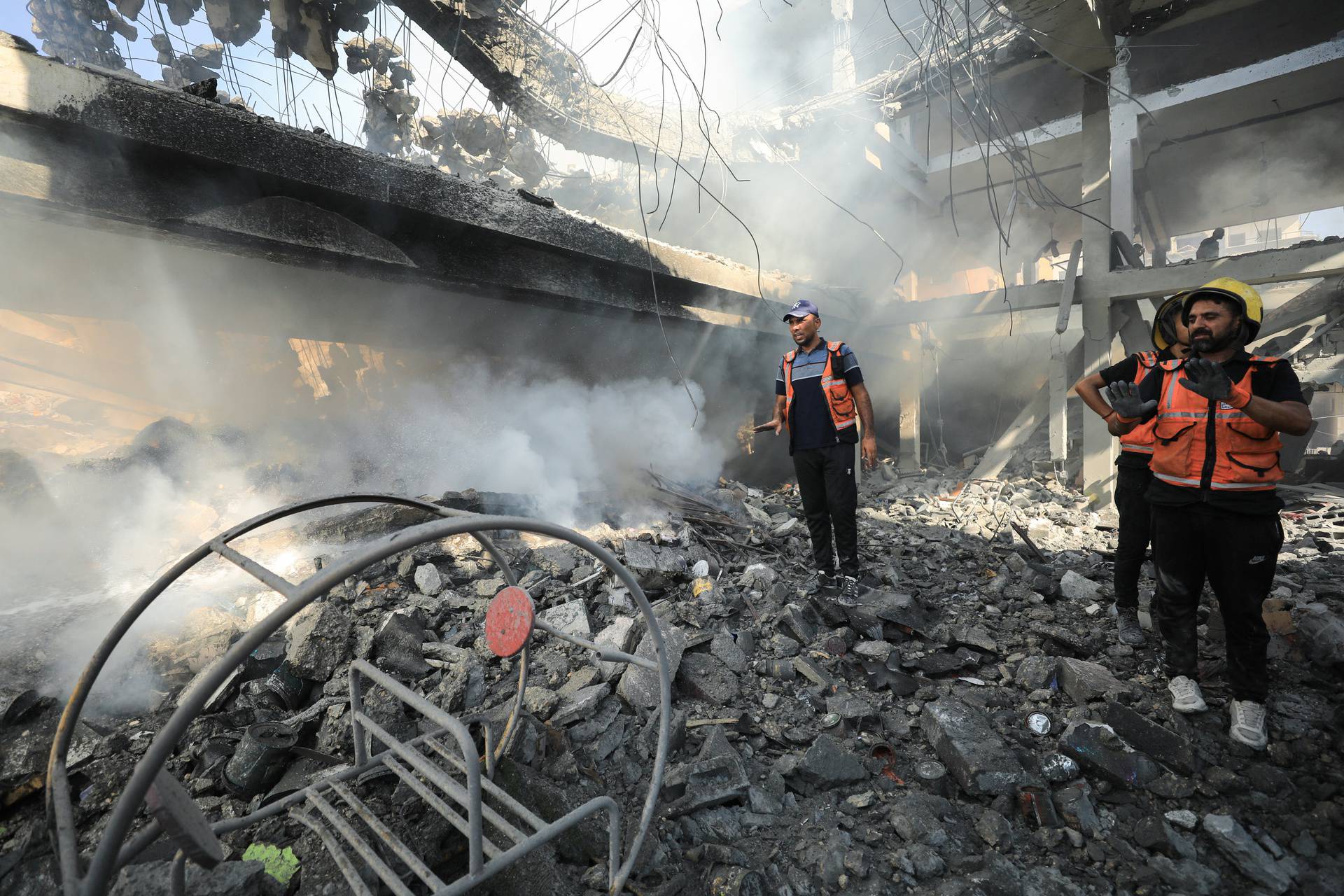 Palestinians inspect the site of an Israeli strike on a college sheltering displaced people, in the northern Gaza Strip