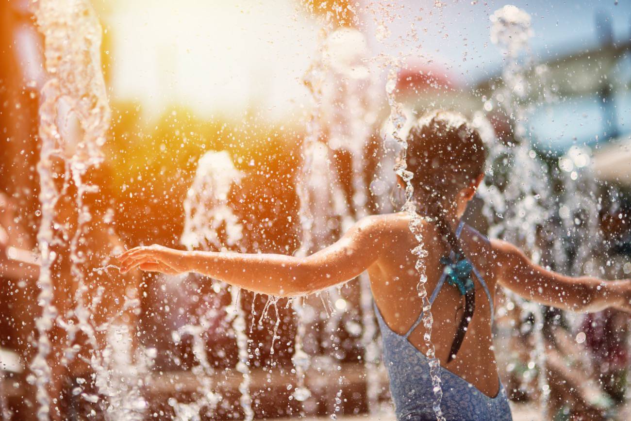 Little girl having fun in water park fountain