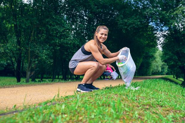 Girl,Crouching,With,Garbage,Bag,Looking,At,Camera,Doing,Plogging