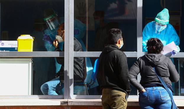 A health worker gives results to a couple as another takes a swab sample for a coronavirus disease (COVID-19) antigen test, in Madrid