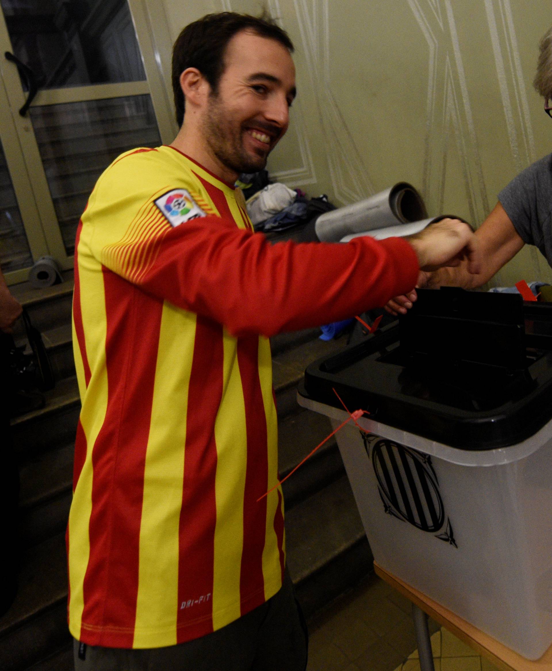 A man, wearing a shirt with the colours of Catalan regional flag, casts his vote in a polling station of the banned separatist referendum in Barcelona