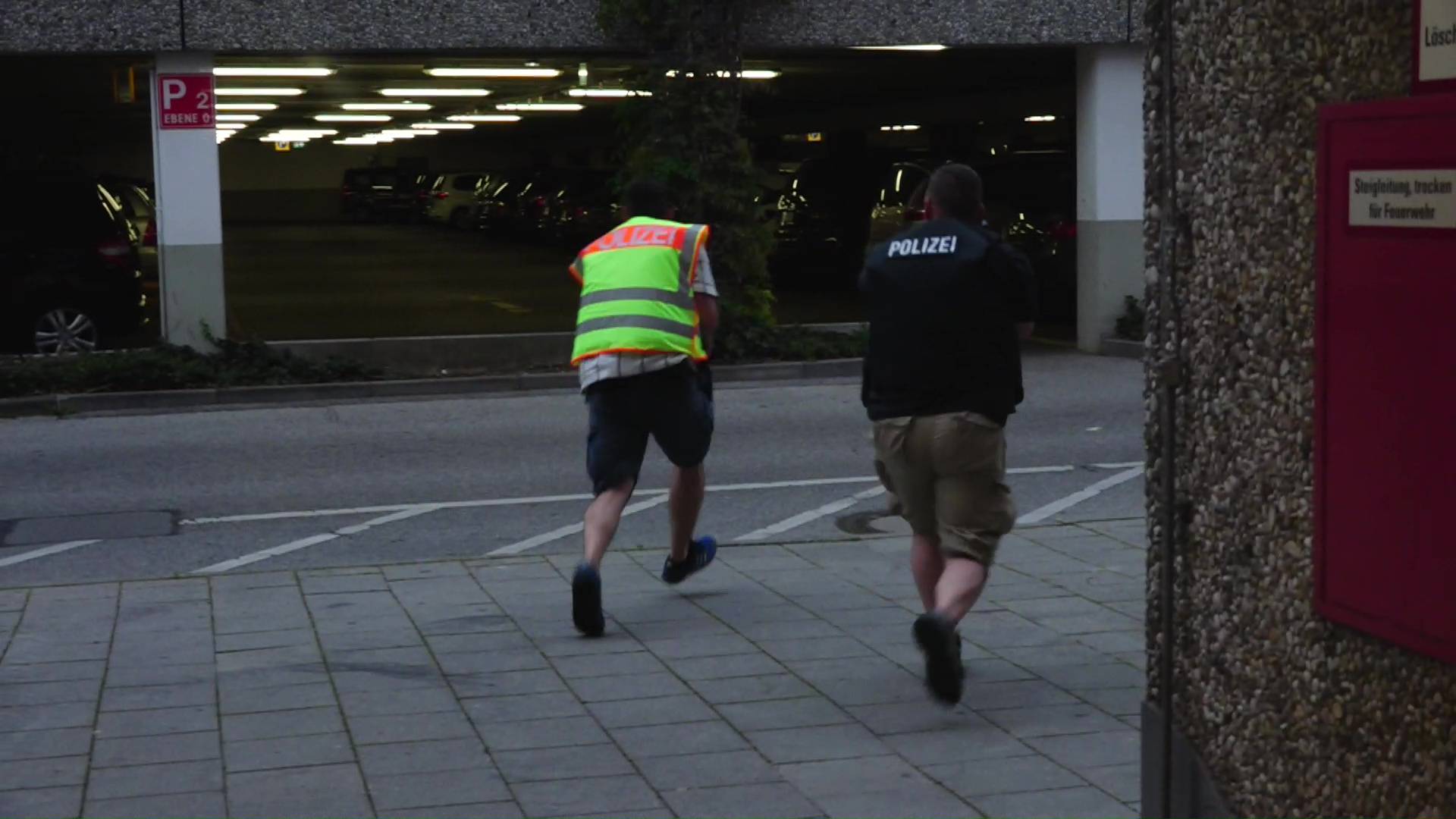 Screen grab shows plain clothes police officers running towards car park of shopping mall during shooting rampage in Munich