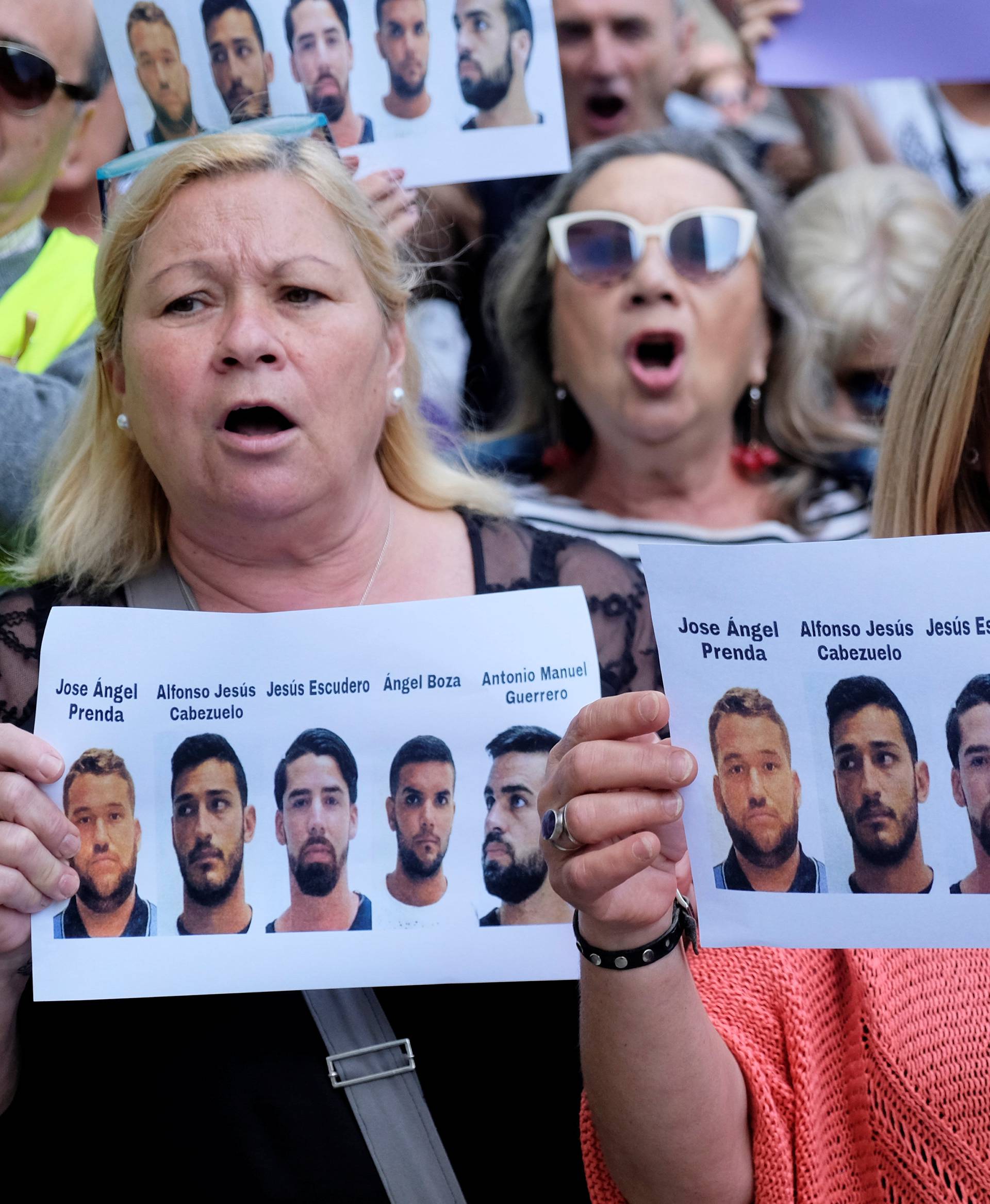 People shout slogans while holding signs during a protest outside the City of Justice in Valencia