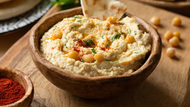 Homemade chickpea hummus bowl with pita chips and paprika