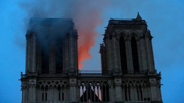 Smoke and flames fill the sky as a fire burns at the Notre Dame Cathedral during the visit by French President Emmanuel Macron (not pictured) in Paris