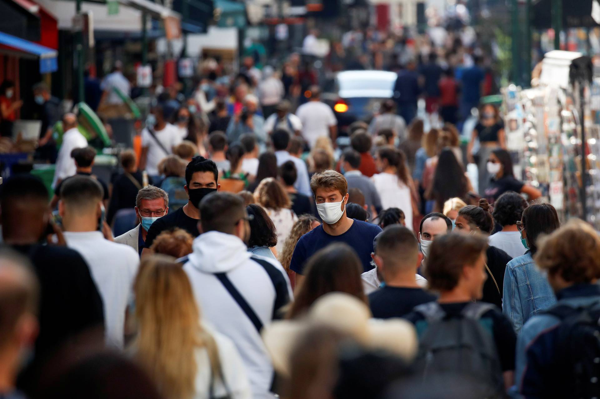 People wearing protective face masks walk in a busy street in Paris