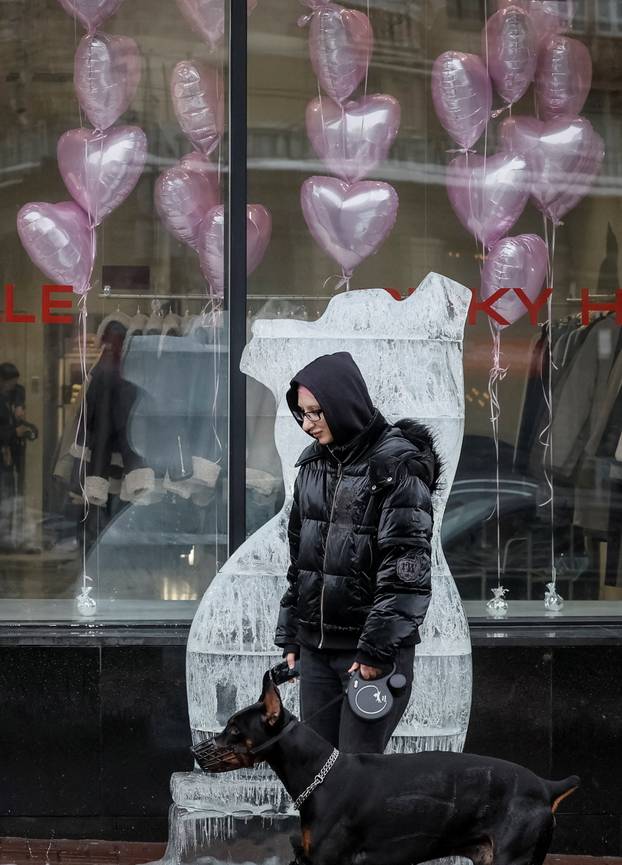 A woman walks past an ice sculpture outside a clothing store advertising winter sales ahead of Valentine's Day celebrations in central Kyiv