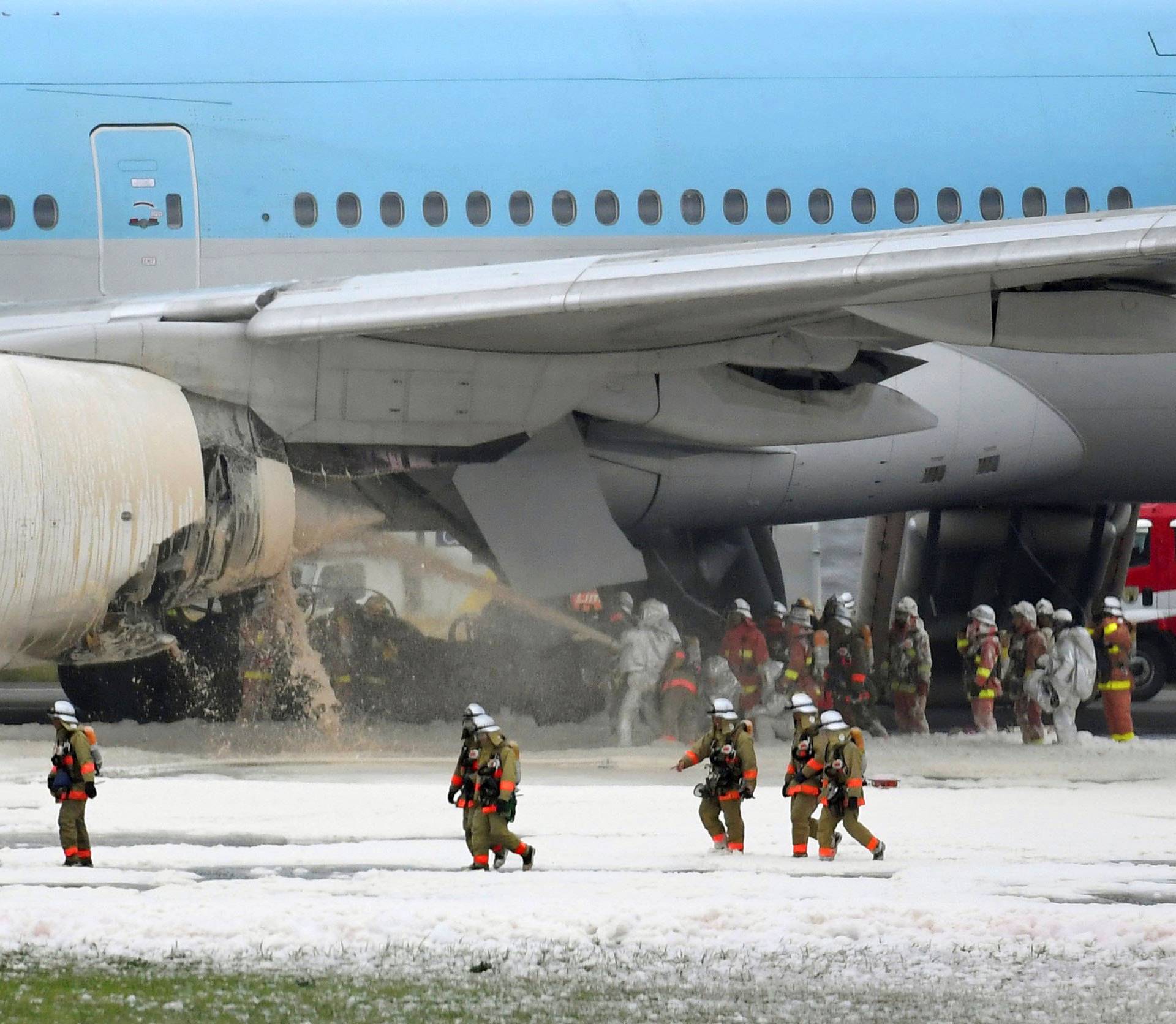 Firefighters spray foam at the engine of a Korean Air Lines plane after smoke rose from it at Haneda airport in Tokyo