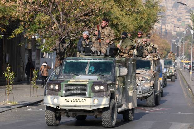 Rebel fighters ride on vehicles, in Damascus