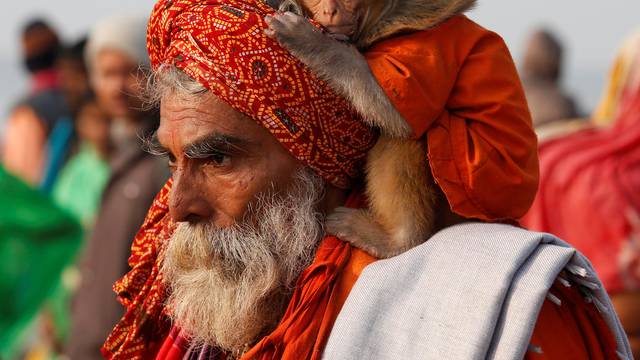 A Sadhu or a Hindu holy man carrying his pet monkey walks after taking a dip at the confluence of the river Ganges and the Bay of Bengal on the occasion of "Makar Sankranti" festival at Sagar Island