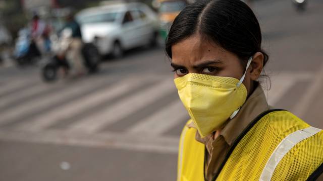 A policewoman wears a mask to protect herself from air pollution at a junction during restrictions on private vehicles based on registration plates on a smoggy morning in New Delhi