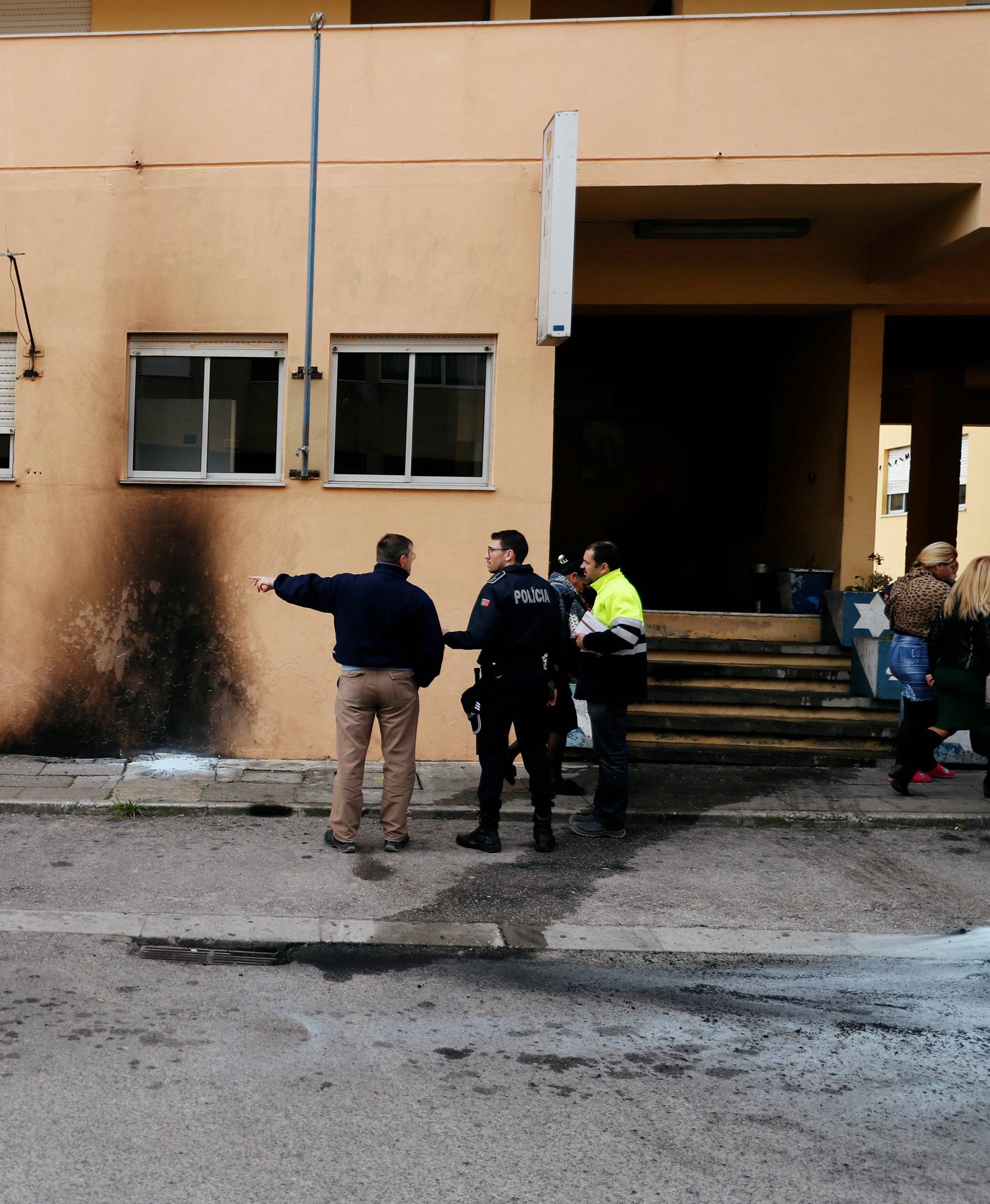 The police officers are seen near the damage caused by molotov cocktails is seen on the police station building at the Bela Vista neighborhood in Setubal
