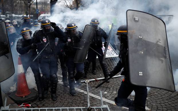 Police officers fire a tear gas during protests against higher fuel prices, on the Champs-Elysee in Paris