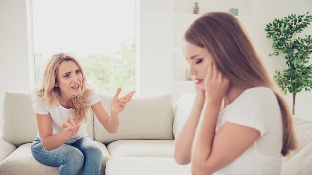 Close up photo unsatisfied two people mum and teenager daughter yelling fighting ignore not listen hide ears sick tired depressed wear white t-shirts jeans in bright flat sit on comfortable sofa