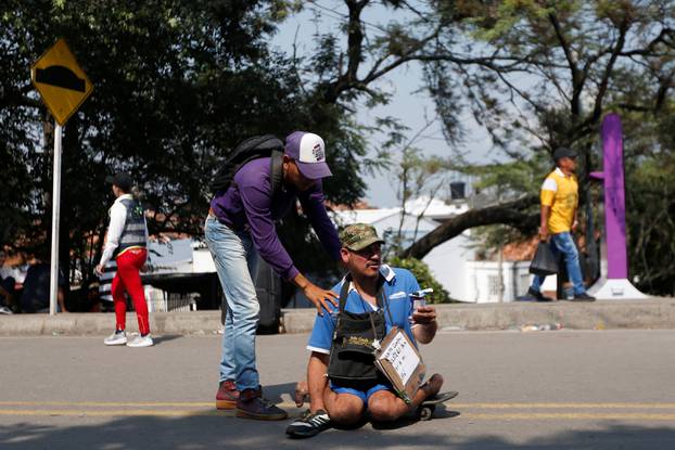 A man helps to push the skateboard of a man with with mobility issues at the Francisco de Paula Santander international bridge in Cucuta