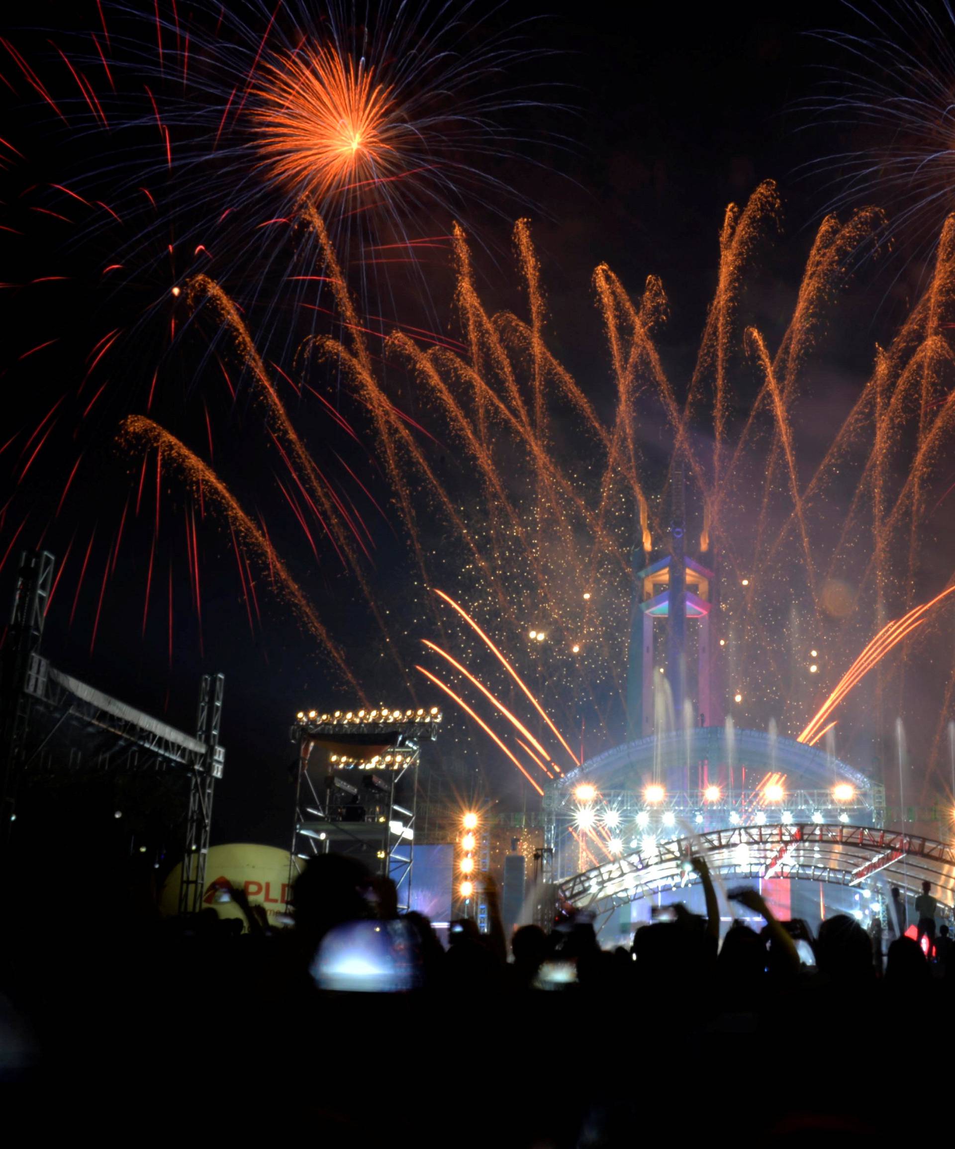 Revellers watch as fireworks explode over the Quezon Memorial Circle during New Year's celebrations in Quezon City, Metro Manila