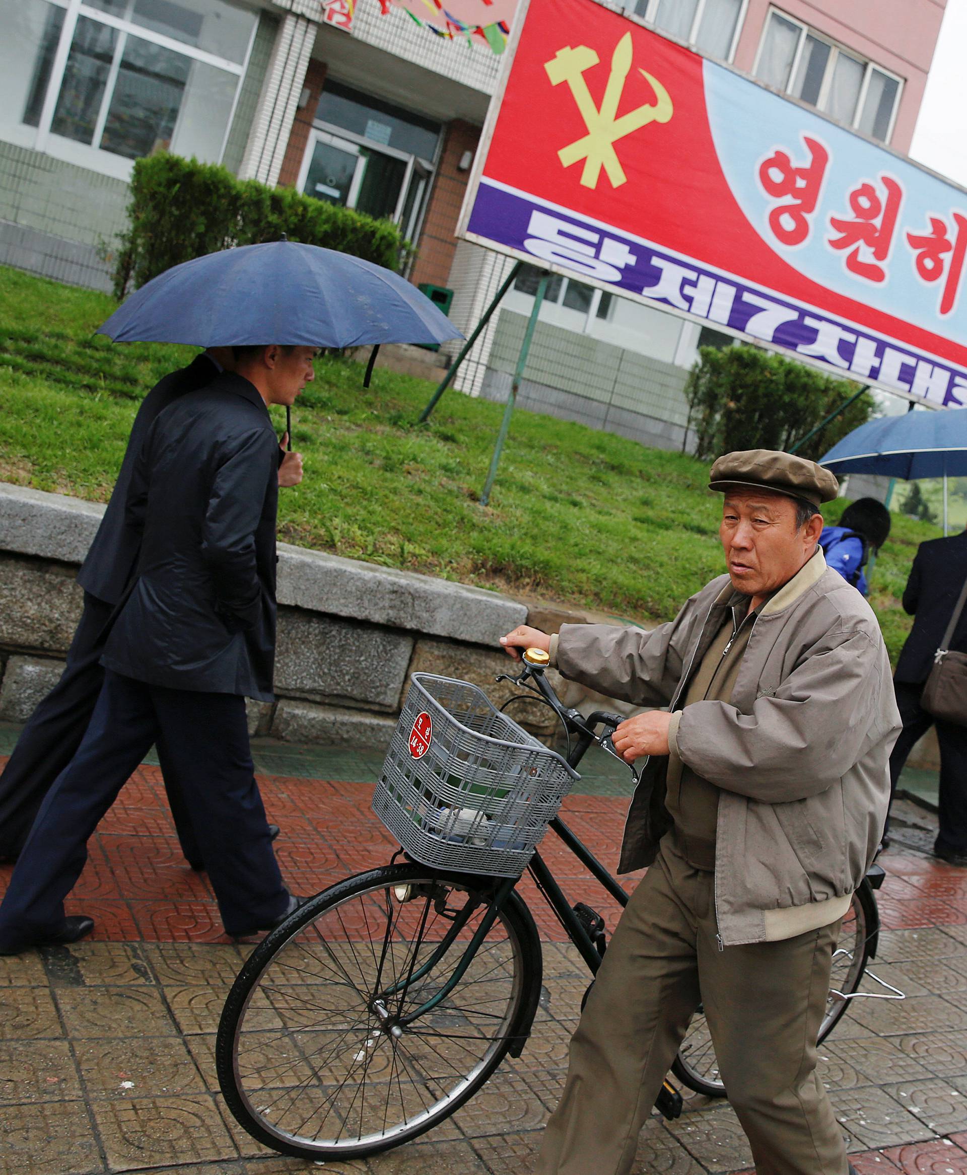 People walk in front of a banner announcing Workers' Party of Korea (WPK) congress placed near April 25 House of Culture, the venue of the congress in Pyongyang