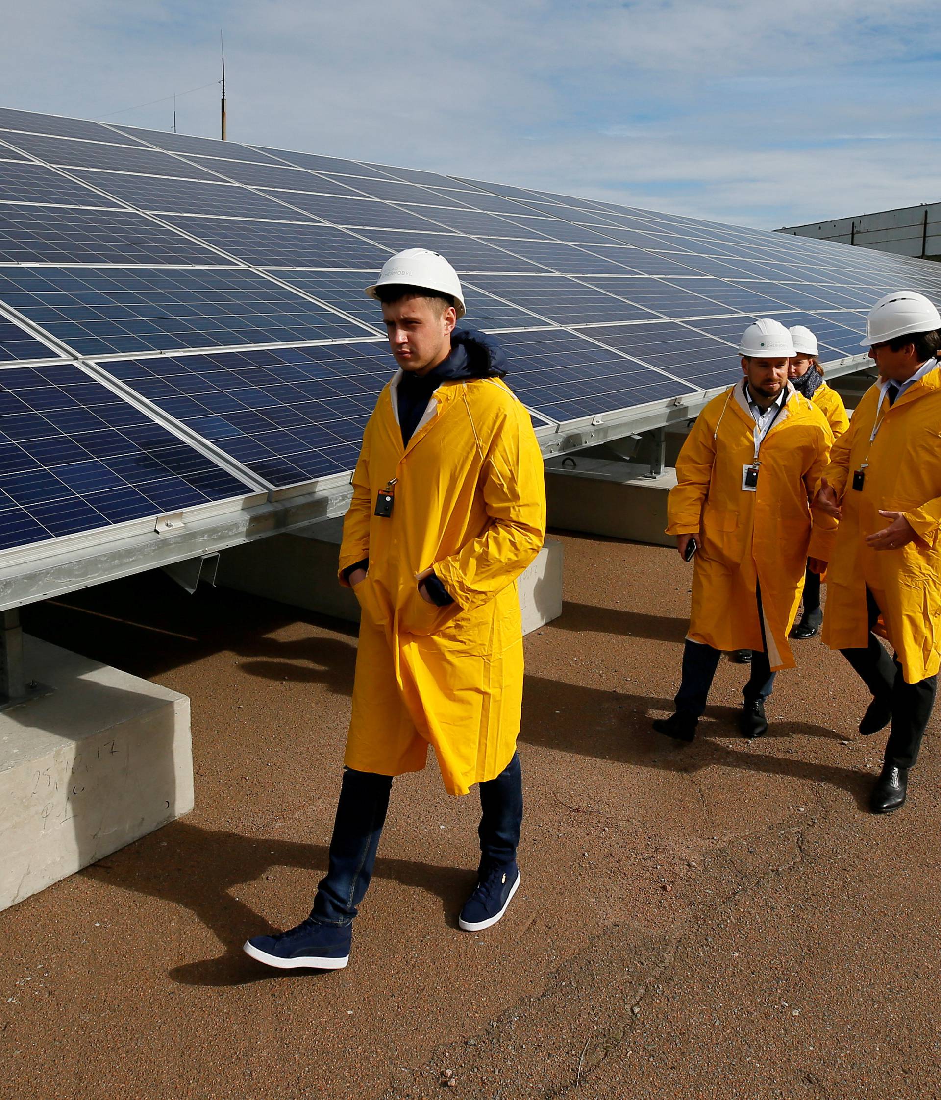 Visitors walk past solar panels at a solar power plant built on the site of the world's worst nuclear disaster, Chernobyl