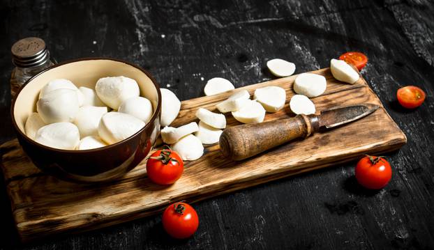 Mozzarella cheese with an old knife and tomatoes.